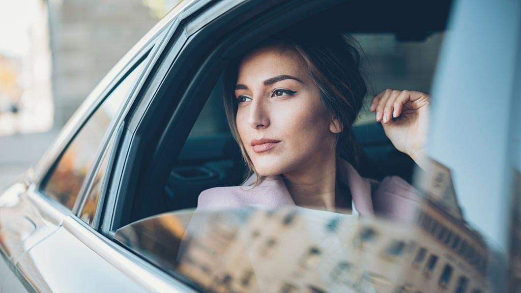 Gelirini arttırmış kadın gayrimenkul danışmanı lüks arabada arka koltukta oturuyor